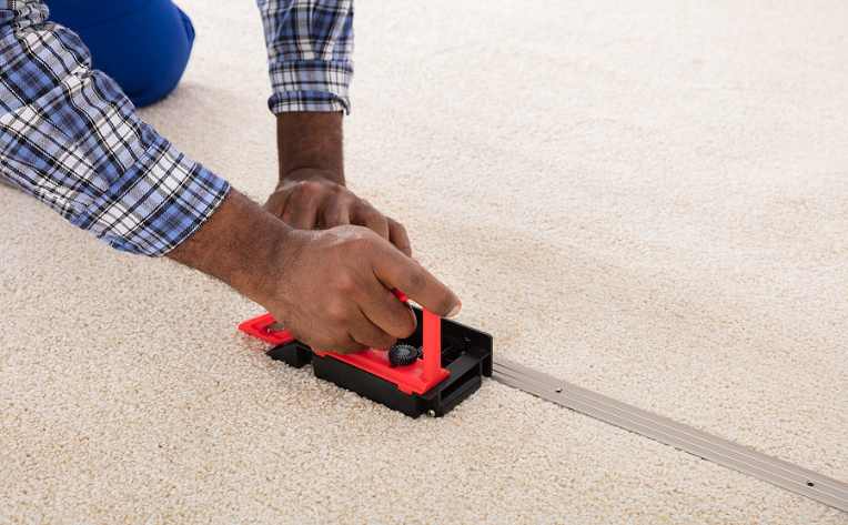 man's hands installing carpet with a seam fitter